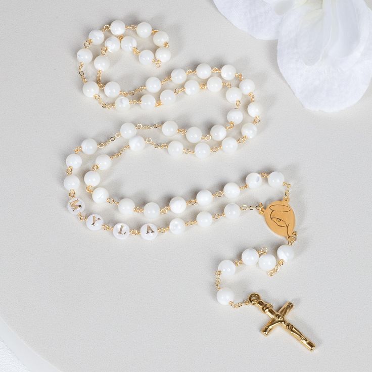 This Personalized Rosary, is ideal as a Baptism gift for a little girl or baby boy or as a gift for a special occasion. It is expertly handcrafted in a traditional style with a contemporary twist utilizing genuine Mother of pearl stone and gold-plated brass wire, which not only gives a touch of nature but also tenderness. The letter beads on the Rosary are also handmade from genuine mother of pearl, and the length is perfect to worn as a dainty Rosary necklace for women. *MATCHING ROSARY BRACELE Spiritual White Cross Jewelry, White Spiritual Cross Jewelry And Charms, Spiritual Letter Beads Necklace For Gift, Handmade Rosary With Round Beads For Baptism, Spiritual 8mm Beads Rosary For Baptism, Handmade Adjustable Rosary For First Communion, White Cross Jewelry For Gift, White Cross Jewelry For Gifts, White Jewelry For Confirmation On Mother's Day