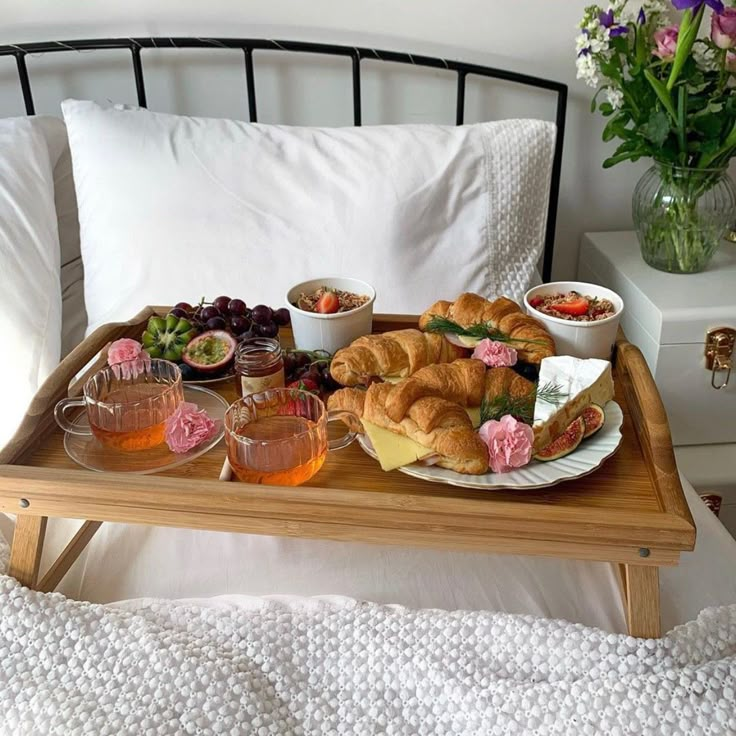 a tray filled with croissants and fruit on top of a bed