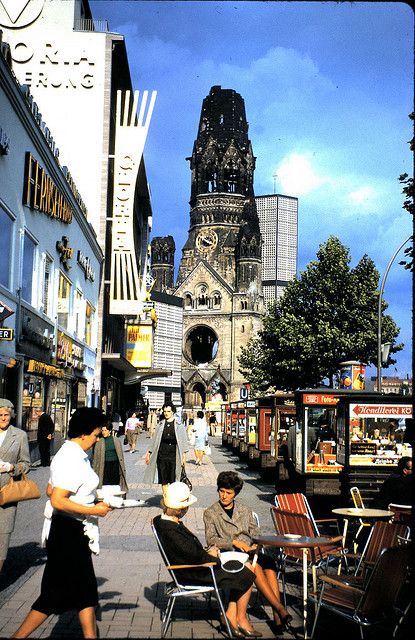 people are sitting on chairs in the middle of a city street with tall buildings behind them