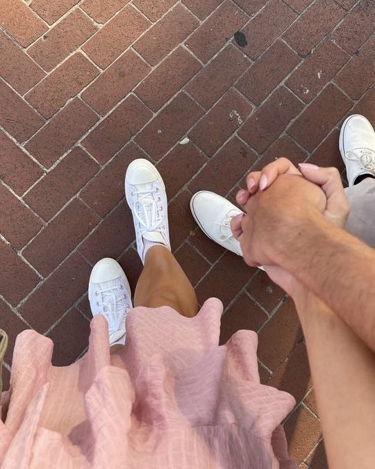 two people sitting on the ground holding hands