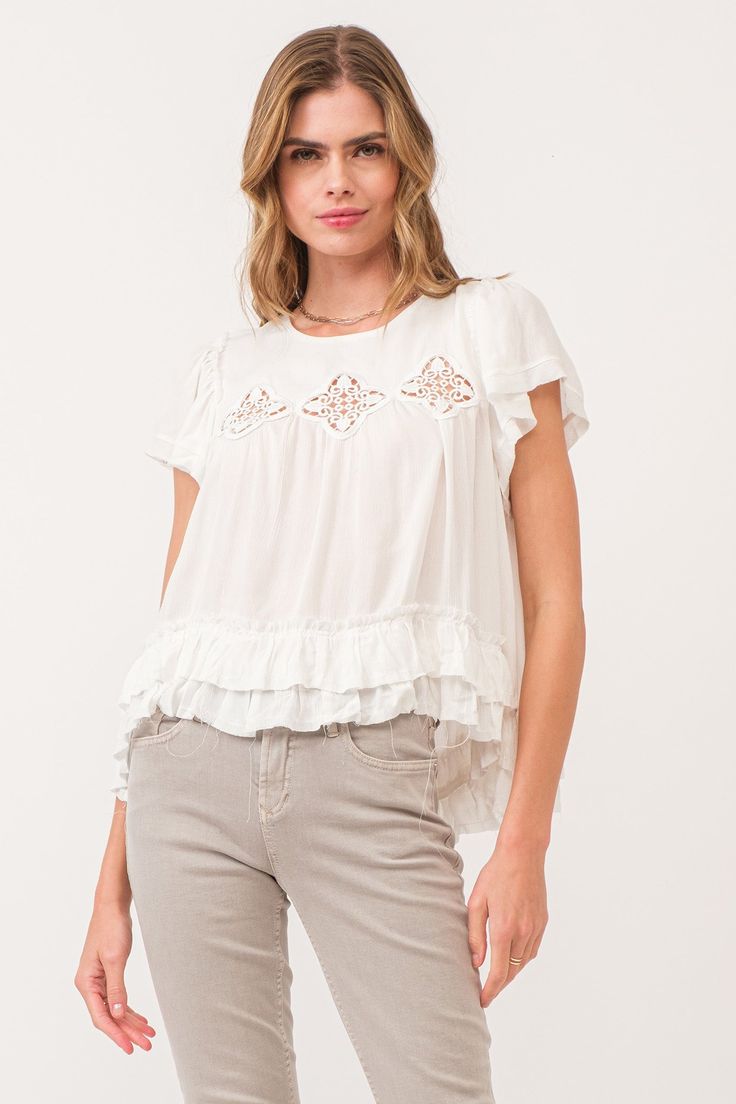 image of a female model wearing a VADA EMBROIDERY MOTIF BLOUSE WHITE DEAR JOHN DENIM Summer Crew Neck Blouse With Ruffle Hem, Spring Blouse With Ruffle Hem And Crew Neck, Summer Tops With Lace Trim And Ruffle Sleeves, Summer Ruffle Sleeve Tops With Lace Trim, Ruffle Sleeve Tops With Lace Trim For Summer, Spring Cotton Ruffle Short Sleeve Top, Bohemian Short Sleeve Top With Ruffle Hem, White Blouse With Ruffles And Flutter Sleeves, Ruffle Sleeve Tops For Summer Layering