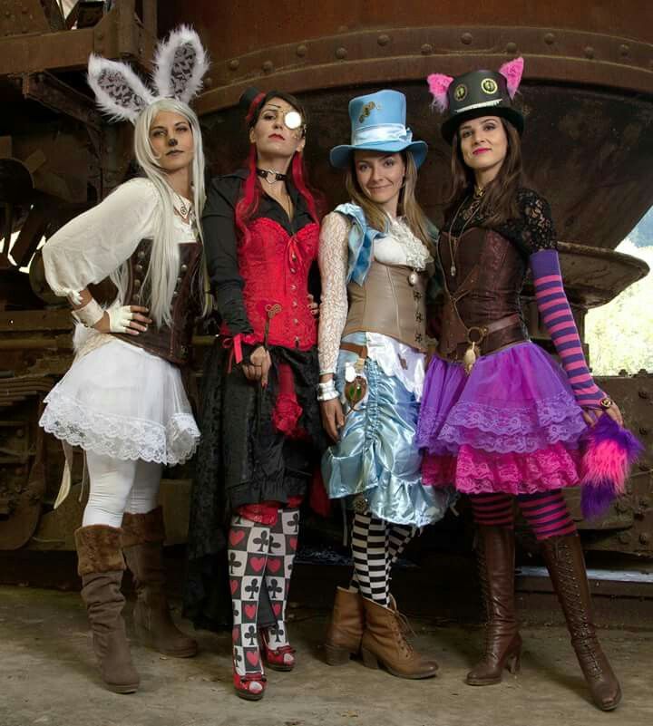 three girls dressed in costumes standing next to an old train car with their eyes closed