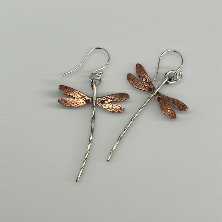 "Dragonfly earrings done in sterling silver & flame patinaed copper. Wings measure approx. 1\" wide and length including earwire is approx. 2 1/4 inch (give or take a bit on the length). Sterling earwires & dragonfly body, copper wings. Flame patina on the copper will vary! These have turned out to be one of my most popular earring creations! due to the hand made nature of these, each earring itself is individually made by hand, there may be slight variances between the photographs and the earri Unique Rust-colored Earrings With Ear Wire, Unique Rust Earrings With Ear Wire, Hammered Silver Earrings Made Of Copper, Hammered Silver Copper Earrings, Silver Hammered Copper Earrings, Artistic Silver-colored Copper Earrings, Artistic Silver Copper Earrings, Hand Forged Silver Copper Earrings, Unique Silver-colored Copper Earrings