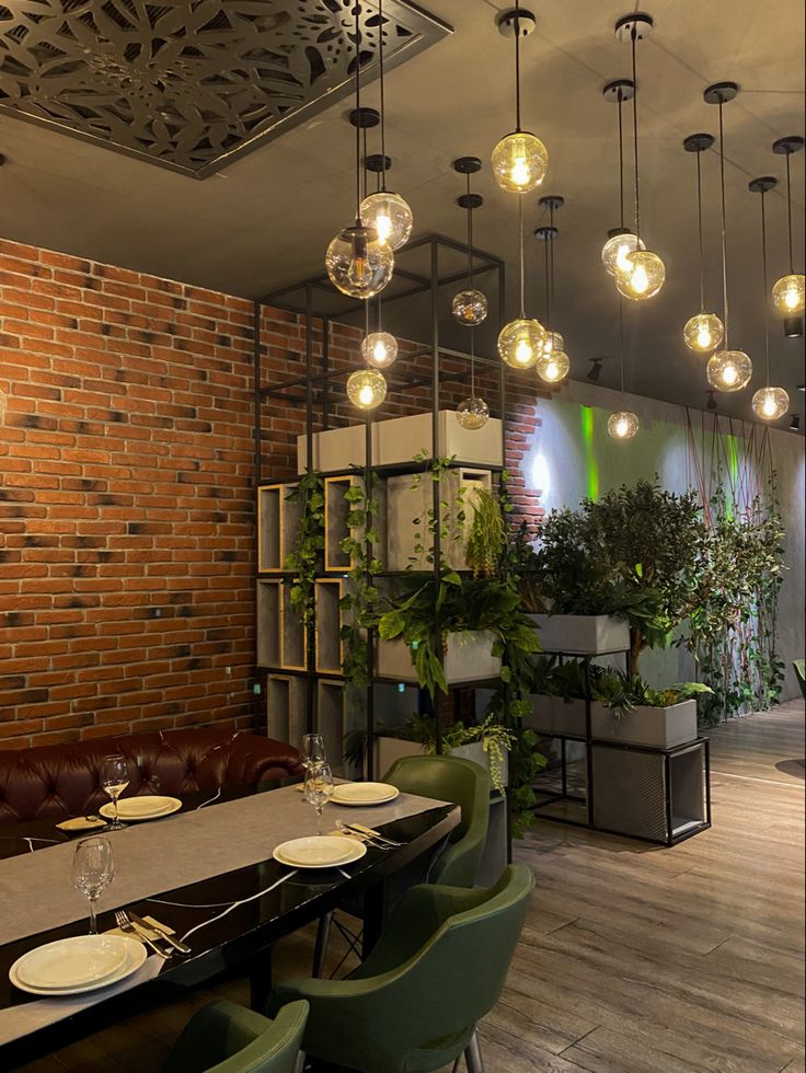 the dining room is set up with green chairs and lights hanging from the brick wall