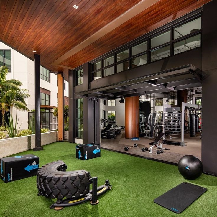 an indoor gym with exercise equipment and yoga mats on the grass in front of it