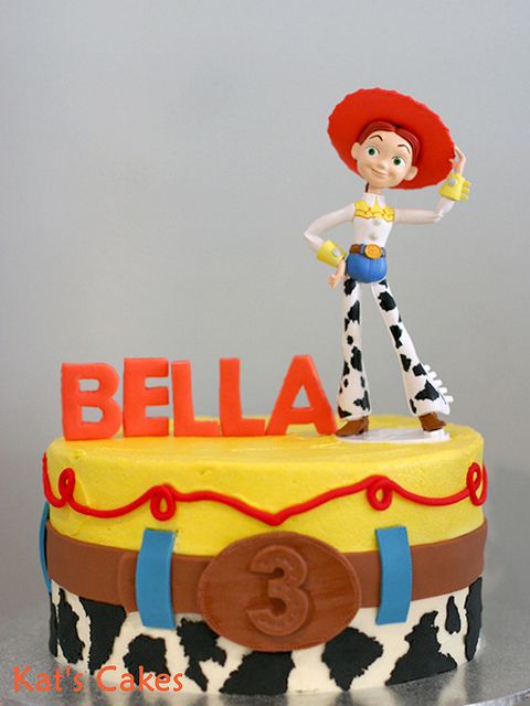 a birthday cake with a toy figure on top and the word'bella'spelled out