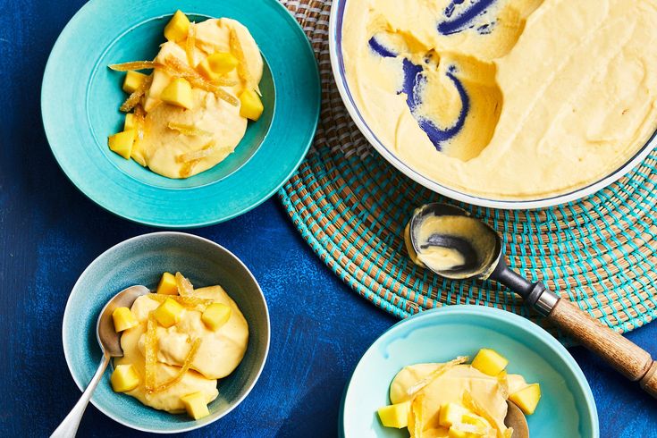 three bowls filled with food sitting on top of a blue cloth covered table next to spoons