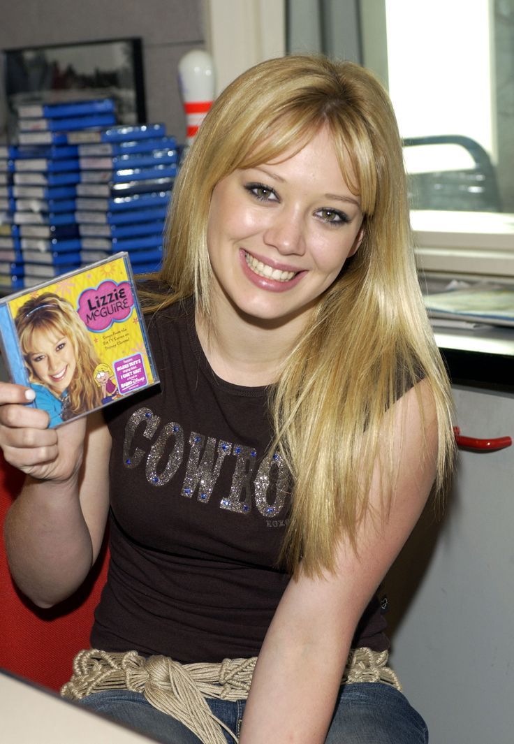 a woman sitting on a chair holding up a dvd in her hand and smiling at the camera