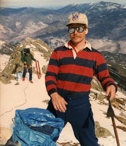 a man standing on top of a snow covered mountain with skis next to him