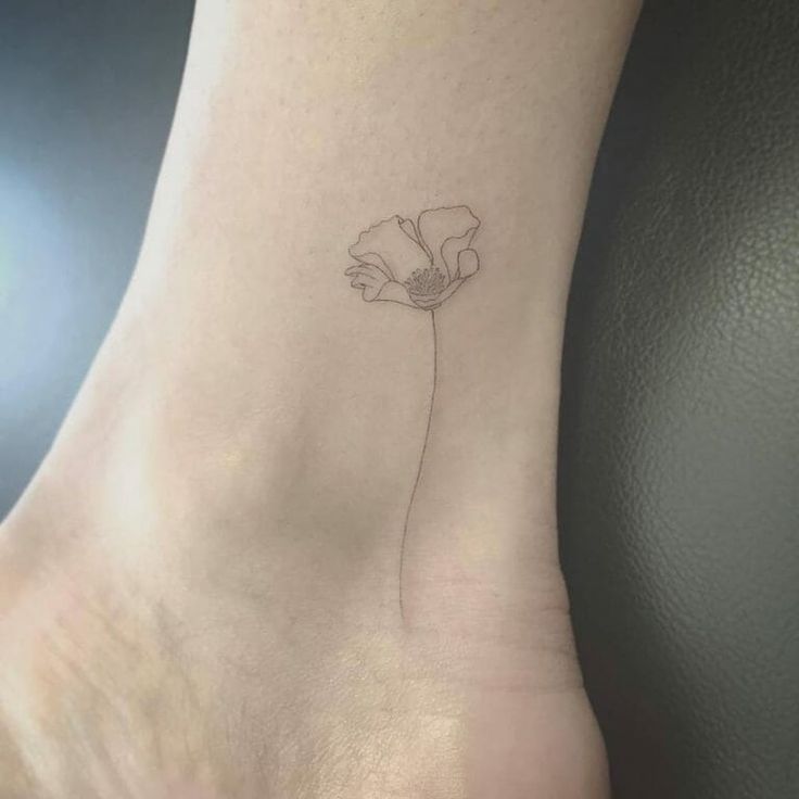 a single flower tattoo on the ankle is shown in black and grey ink, with an outline