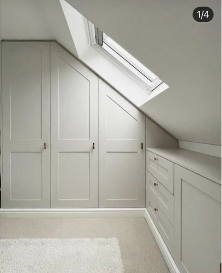 an attic bedroom with white cabinets and carpeted flooring, skylight above the closet