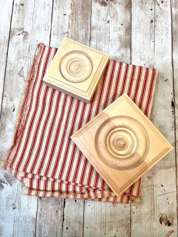 two wooden coasters sitting on top of a red and white striped napkin