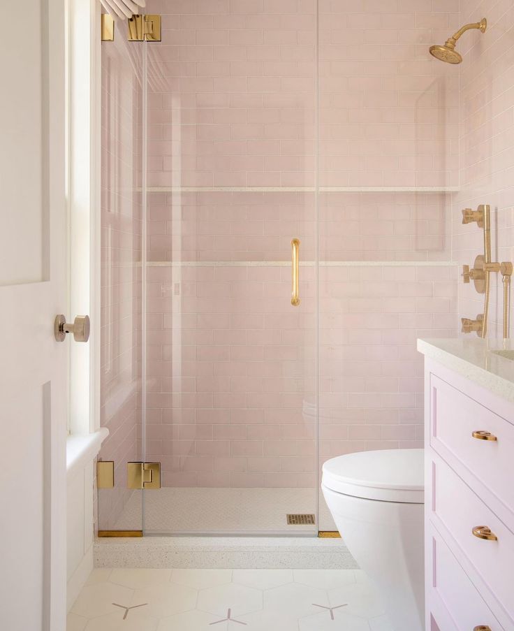 a bathroom with pink tile and gold fixtures