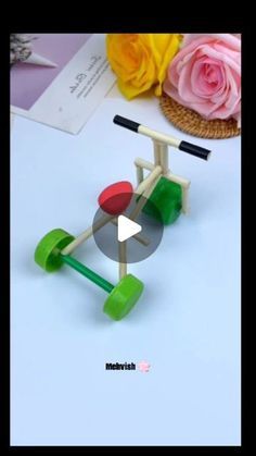 a toy scooter made out of wooden sticks and colored plastic wheels on a table