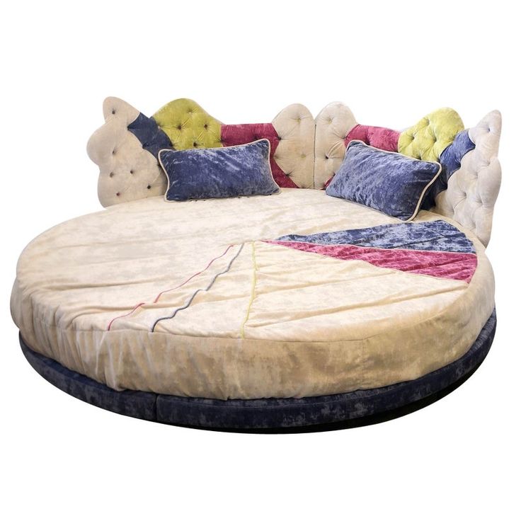 a round bed with several pillows on it and a pillow in the shape of a circle