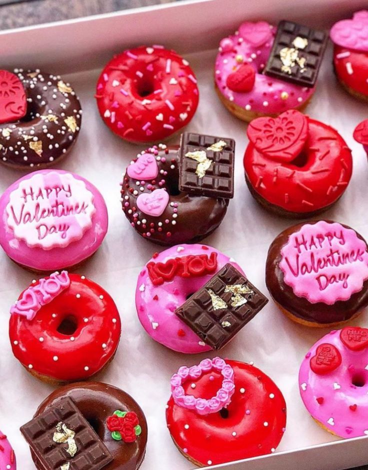 a box filled with lots of different flavored donuts covered in chocolate and pink frosting