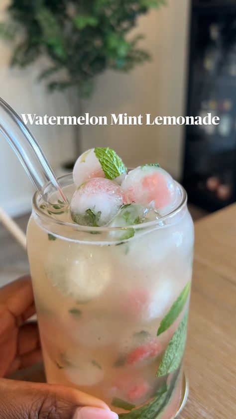 a person holding a glass filled with ice and watermelon mint lemonade drink