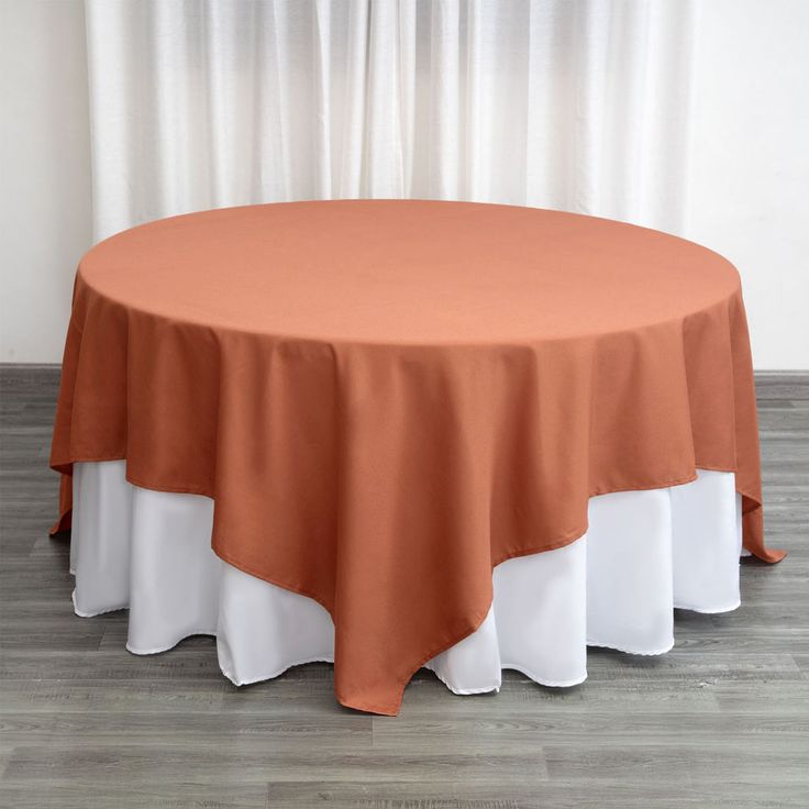 an orange and white table cloth on top of a round table