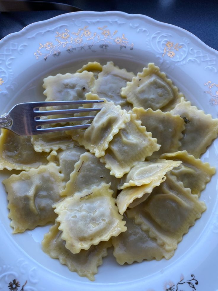 a white plate topped with ravioli and a fork