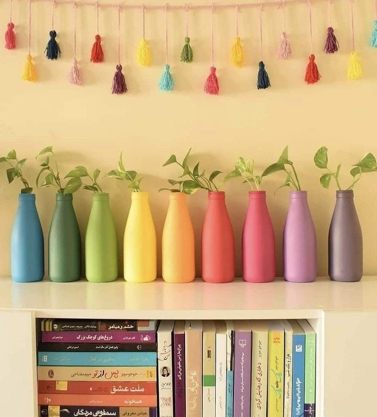 the bookshelf is full of colorful vases with plants growing out of them