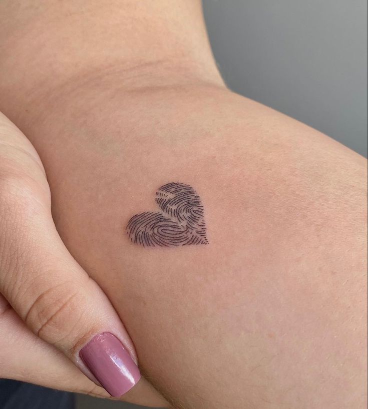 a woman's arm with a tattoo on it that has a fingerprint in the shape of a heart