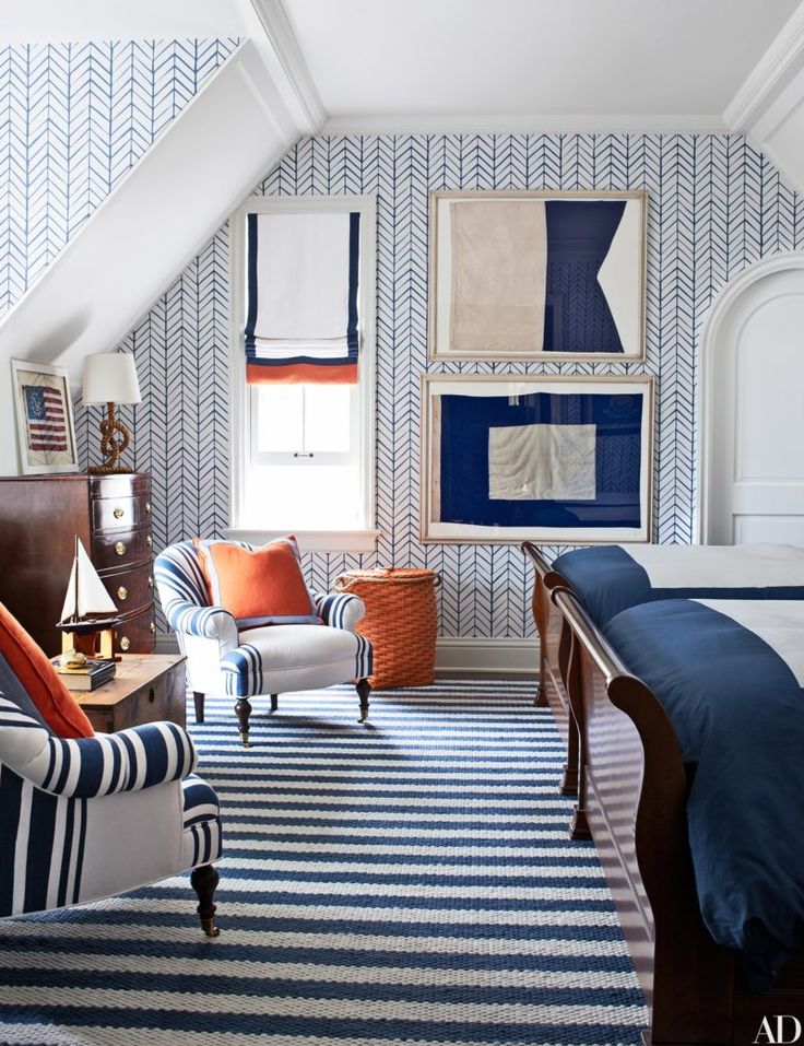 an attic bedroom with blue and white striped rugs on the floor, two chairs in front of a bed