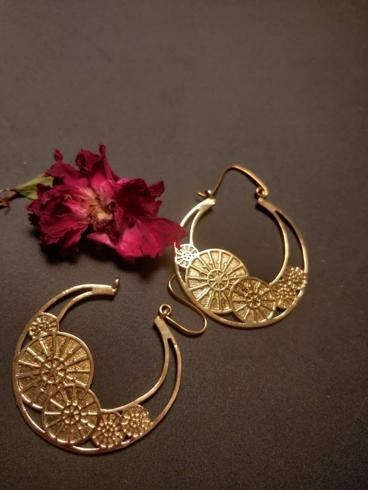 "Transform your look into an eye-catching masterpiece with our Sunwheel Earrings. Handmade with love and crafted from 100% brass, these Gold toned earrings feature a striking Mandala pattern with an edgy Megatron inspired design and intricate hook detailing. Perfect for any occasion, whether it's a yoga session, boho festival, or your special day as a boho bride, these earrings are versatile enough to complement any style. Channel your inner goddess and radiate positive energy with these tribal danglers that also serve as healing jewelry. Elevate your jewelry collection with these must-have Sunwheel Earrings. Order now and experience the beauty and power of handmade boho adornments." Bohemian Teardrop Jewelry With Artistic Design, Vintage Brass Danglers, Unique Brass Earrings For Wedding, Unique Brass Wedding Earrings, Handmade Vintage Spiral Jewelry, Festive Vintage Brass Earrings, Gold Teardrop Earrings With Artistic Design, Vintage Round Earrings For Festivals, Bohemian Brass Danglers For Pierced Ears