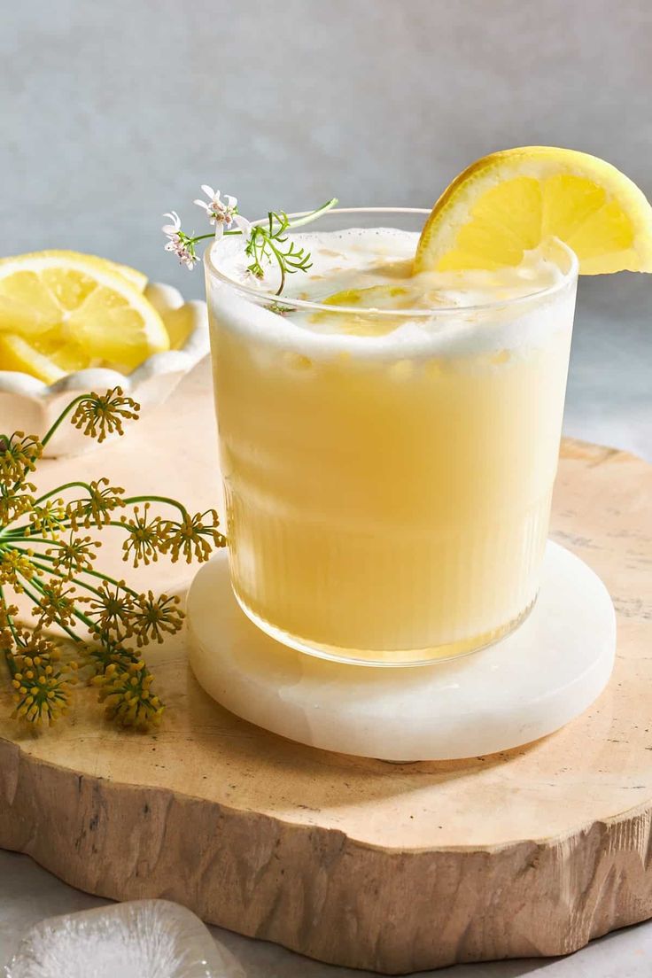 a drink with lemon and rosemary garnish on a wooden board