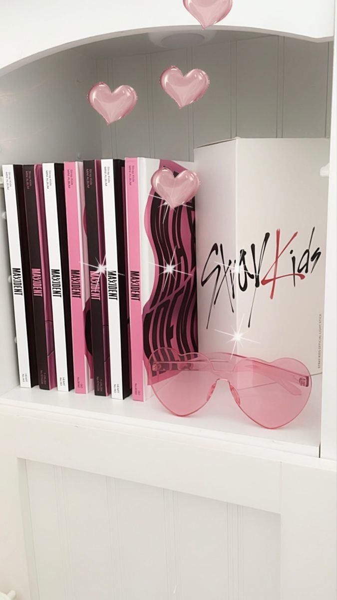 a book shelf filled with books and pink heart shaped glasses on top of each other