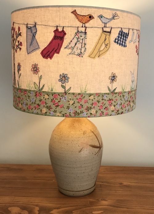 a lamp that is sitting on top of a wooden table with clothes hanging from a line