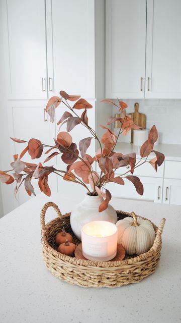 a white vase filled with flowers and candles on top of a counter next to a candle