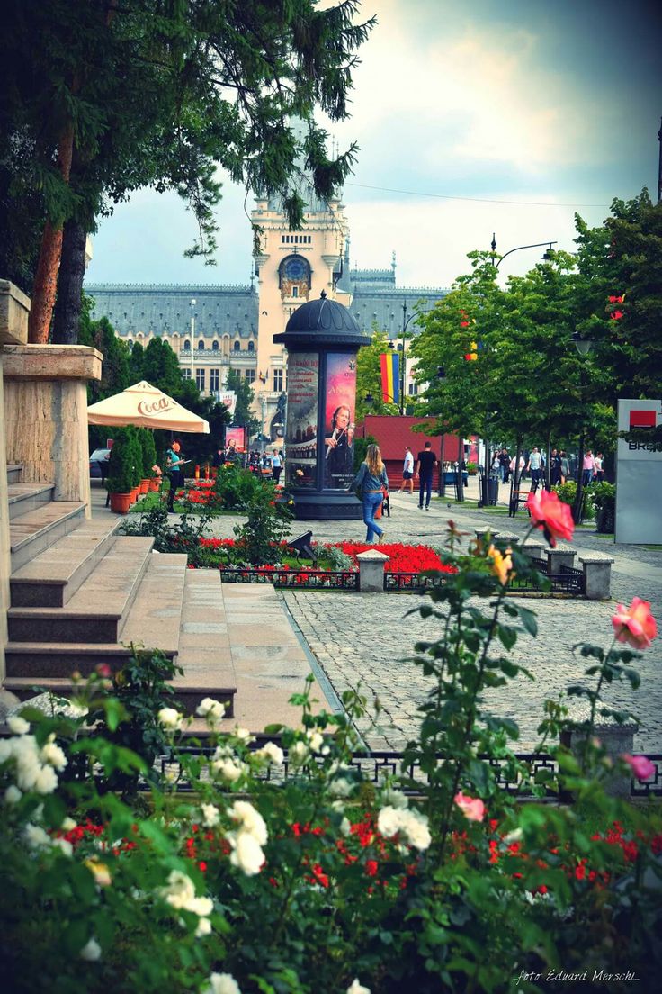 people are walking around in an open area with flowers and umbrellas on the ground