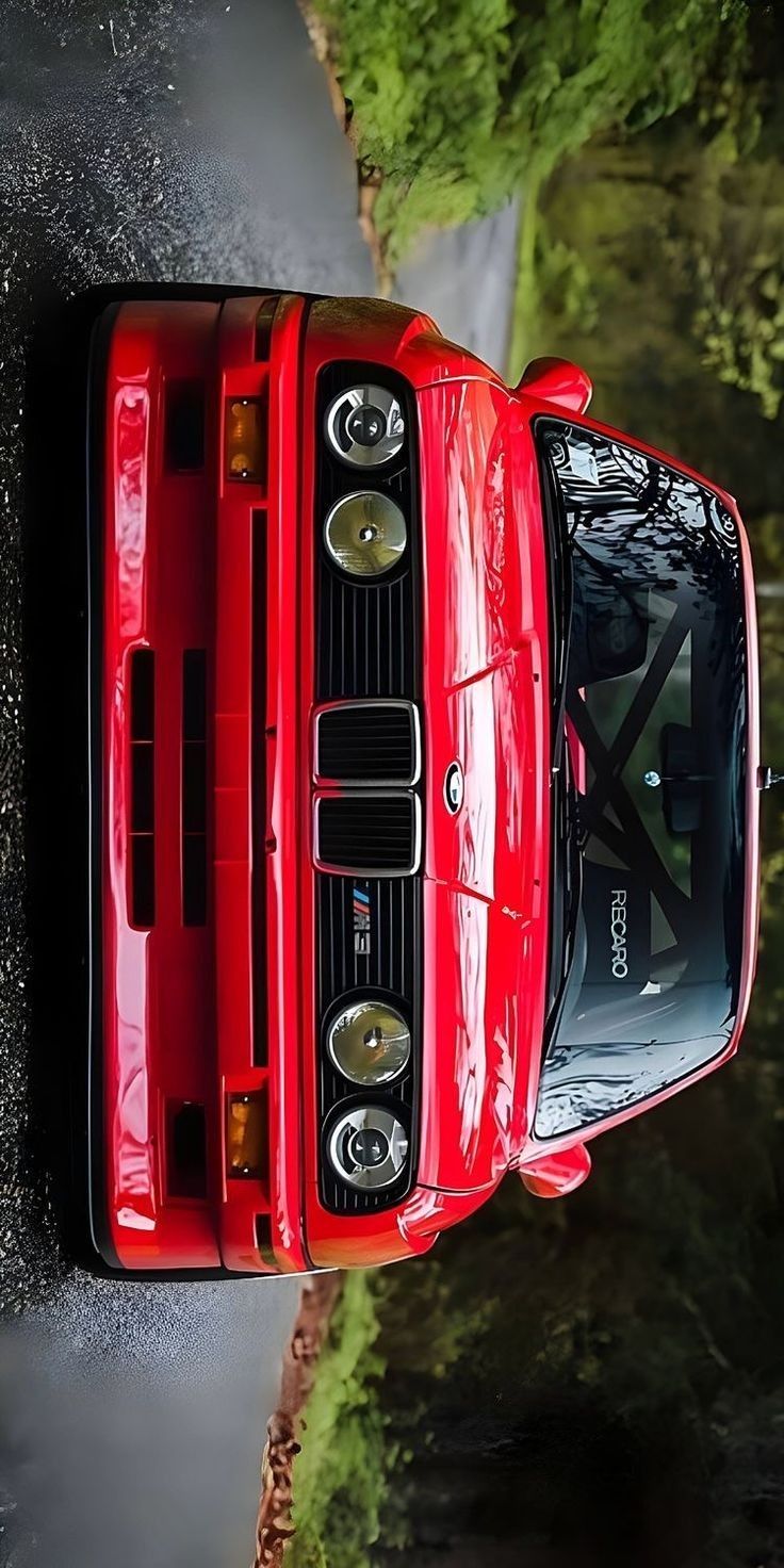 an overhead view of a red sports car parked on the side of a road with trees in the background