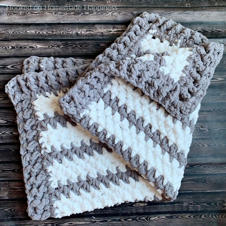 two gray and white crocheted dishcloths sitting on top of each other