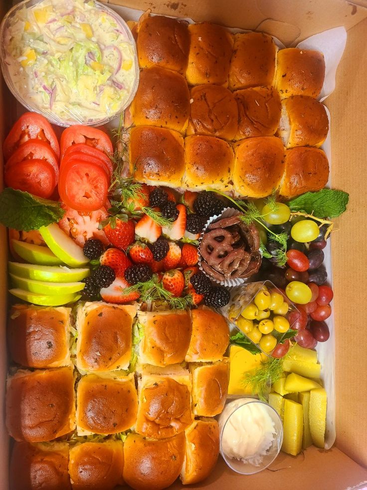 a box filled with lots of different types of sandwiches and fruit on top of it