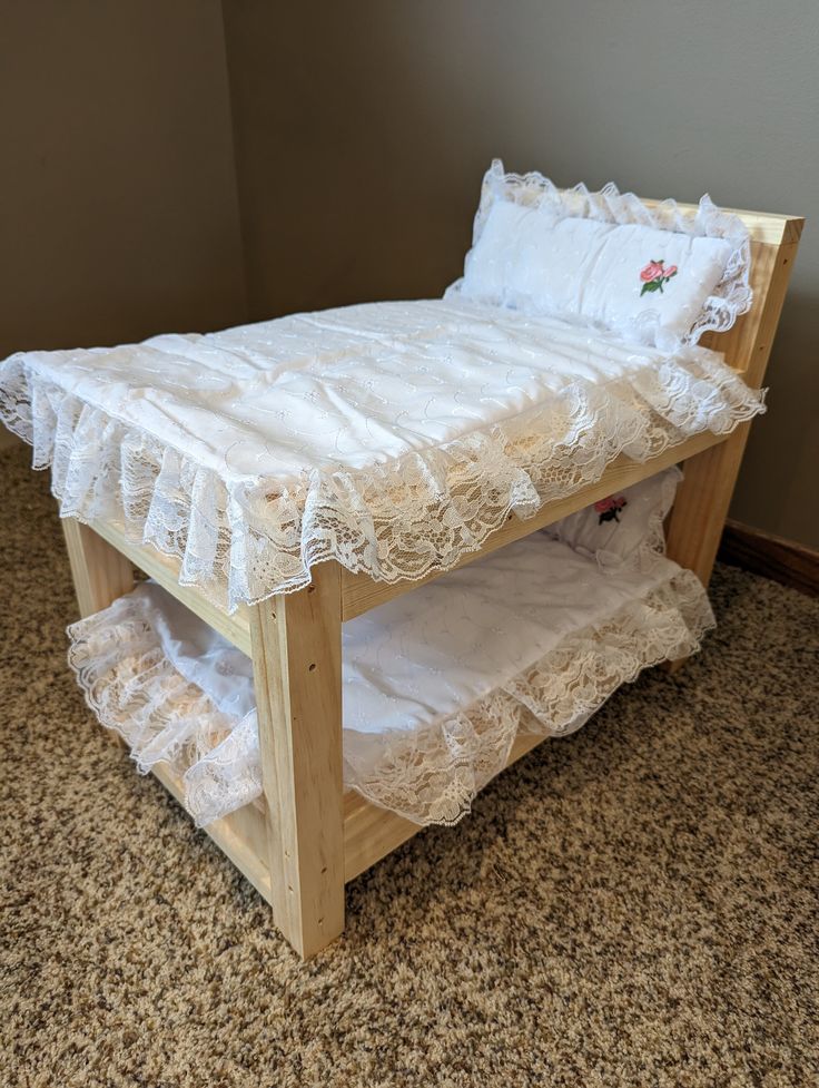 a wooden bed with white ruffled bedspread on it's bottom shelf