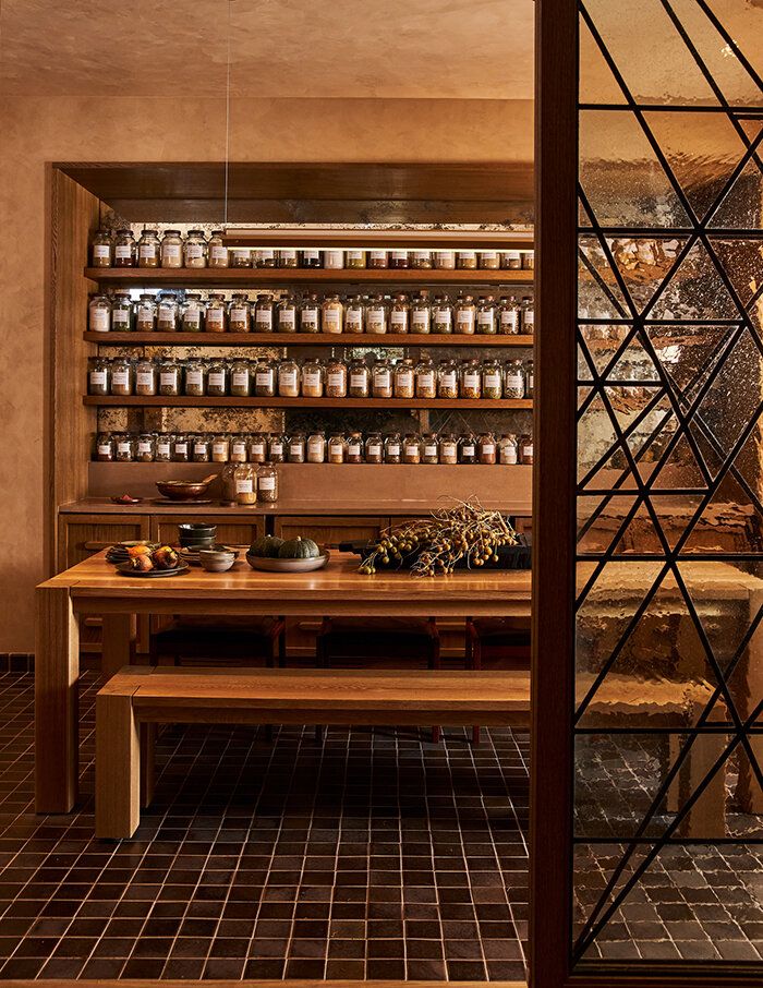 a wooden table sitting next to a shelf filled with jars