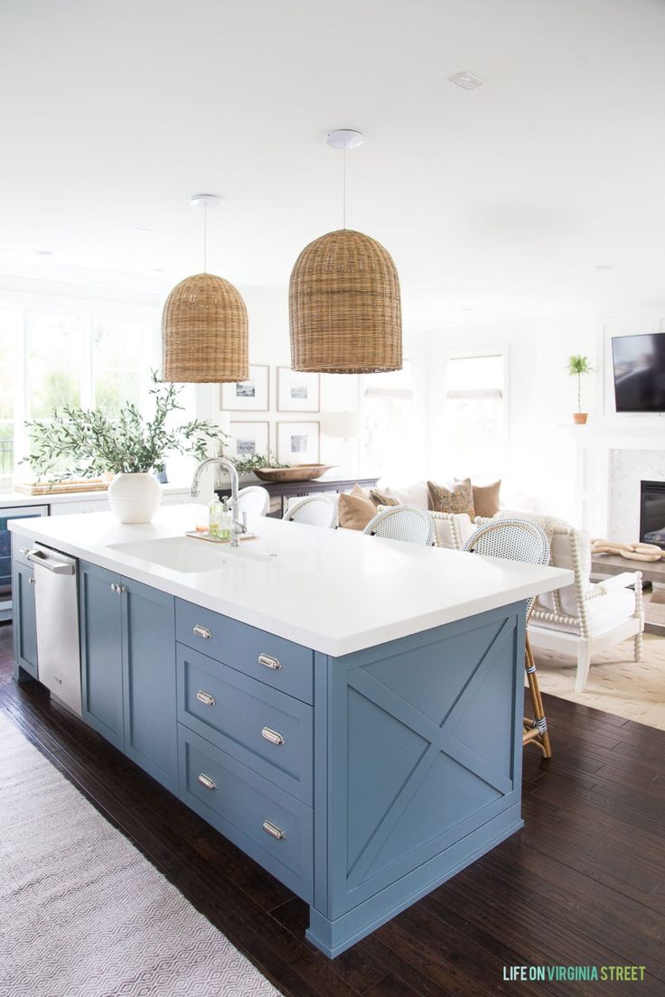 a large kitchen with blue cabinets and white counter tops in front of a fire place