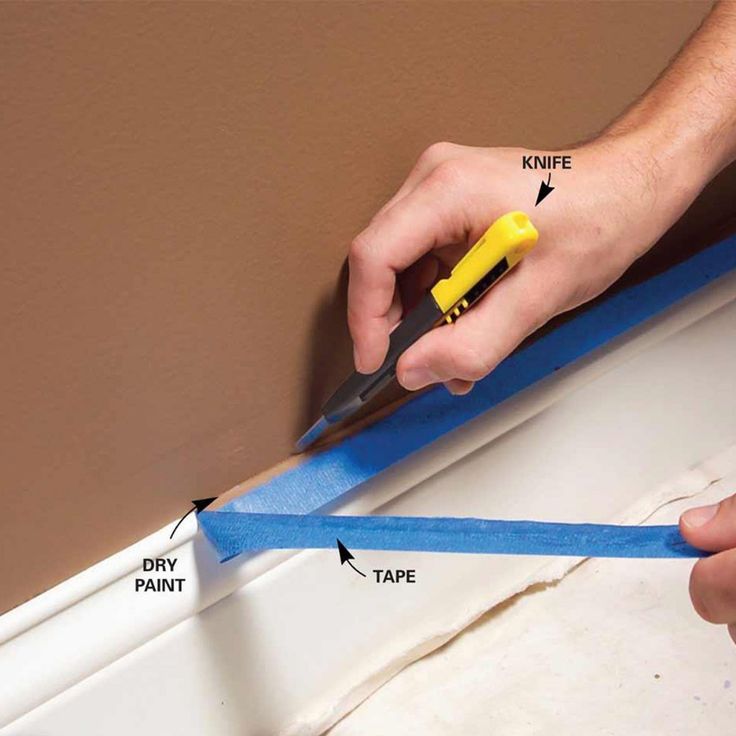 a man is cutting blue tape with a pair of scissors on the edge of a window sill