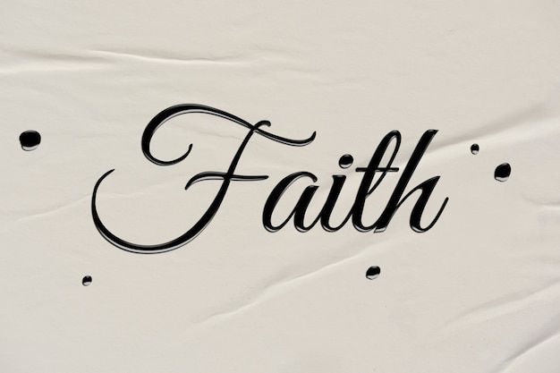 the word faith is written in black ink on a white sheet of paper with polka dots