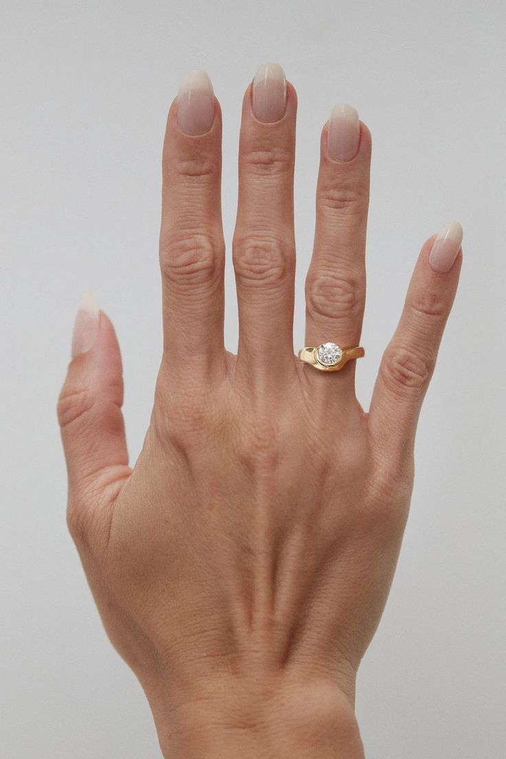 a woman's hand with a diamond ring on her left thumb and the middle finger