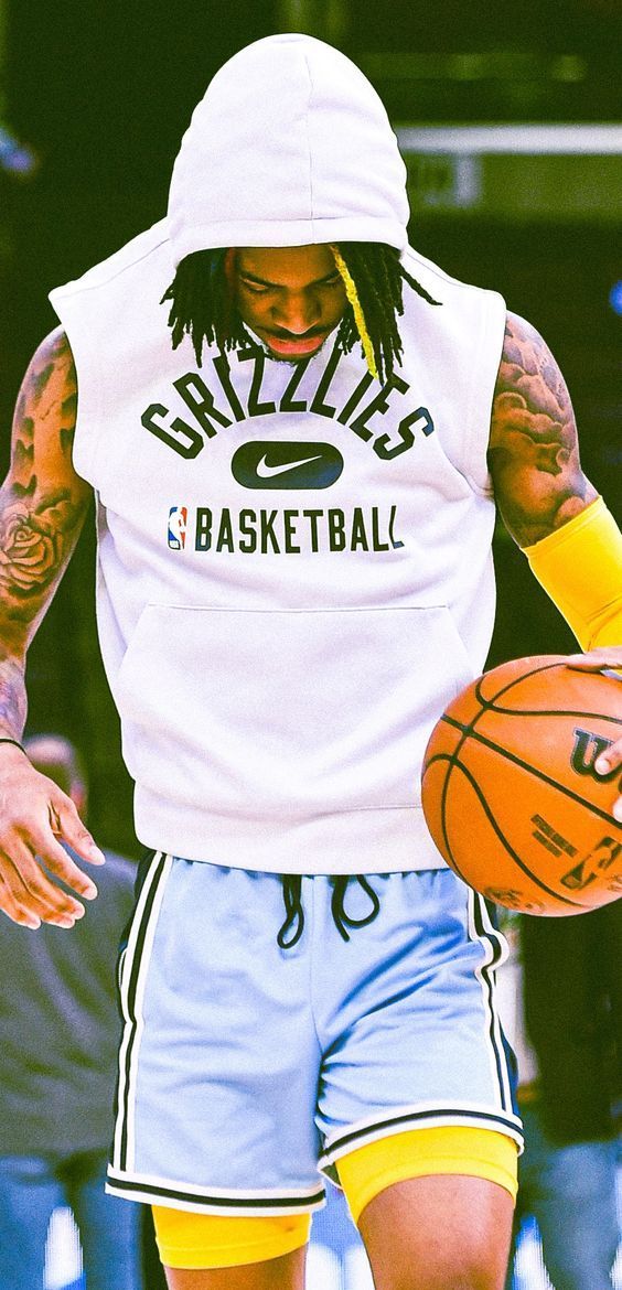 a man with dreadlocks holding a basketball in his right hand and wearing a white hoodie