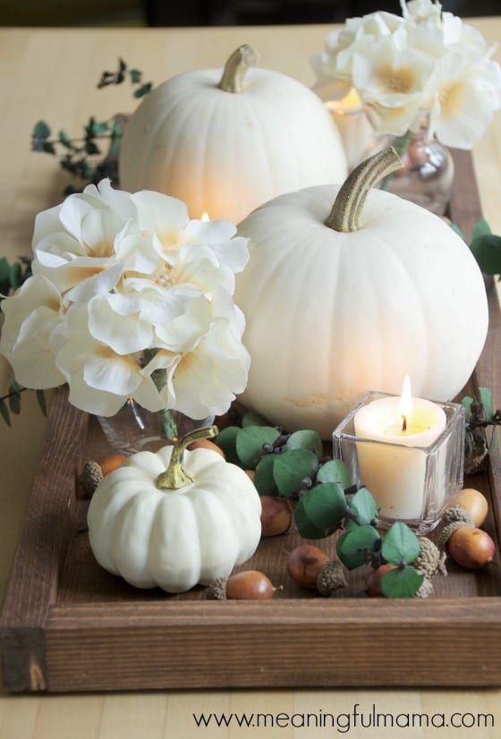 white pumpkins and flowers on a wooden tray with candles in the center, surrounded by other autumn decorations