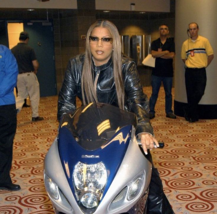 a woman riding on the back of a blue and silver motorcycle