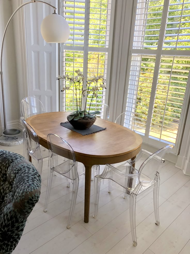 a dining room table with clear chairs and a potted plant on top of it