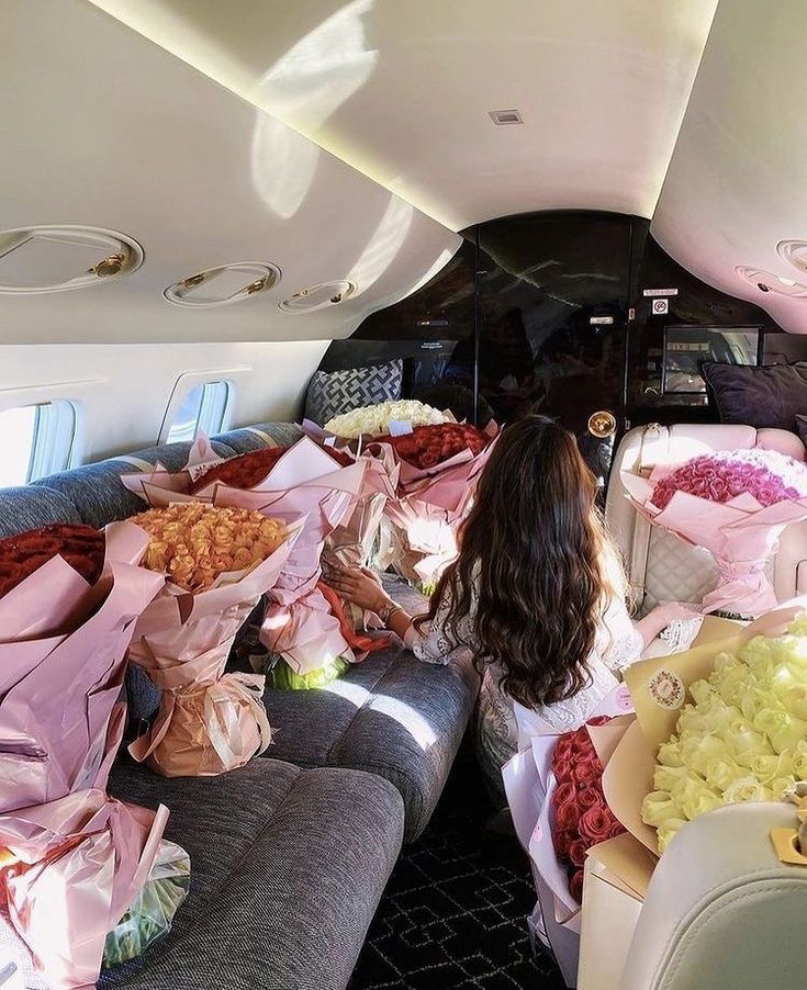 a woman sitting on the back of an airplane filled with lots of flowers and food