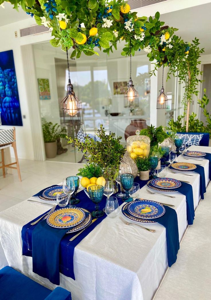 the table is set with blue and white plates, silverware, lemons, and greenery