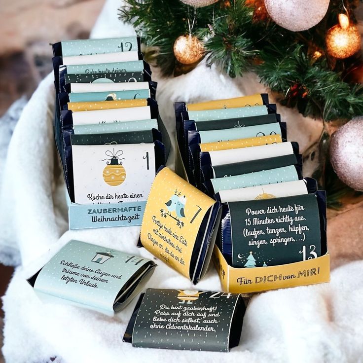 several different types of christmas cards sitting on a white blanket next to a christmas tree