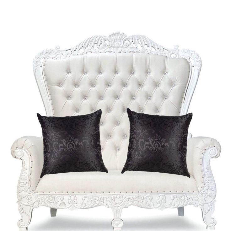 a white couch with two black pillows on it's back and one in the middle