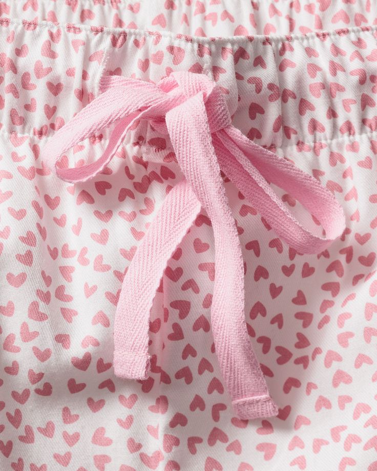 Like joyful confetti, the little pink hearts dance across the fabric as if batting their eyelashes. This classic pajama set is accented with light pink piping and finished with pearl buttons. The fabric is made from 100% of the finest quality cotton and brushed for added softness, making the sleepwear feel absolutely luxurious, getting cozier with each wash. You will tucked in luxury and off to dreamland. Bonne nuit. Pink Spring Bedtime Sets, Pink Bedtime Sets For Spring, Pink Cotton Sleepwear With Elastic Waistband, Sweet Pink Sleepwear, Sweet Pink Sleepwear For Loungewear, Pink Bedtime Sets, Pink Heart Print Sleepwear For Pajama Party, Sweet Pink Sleepwear For Sleepover, Pink Sweet Sleepwear For Bedtime